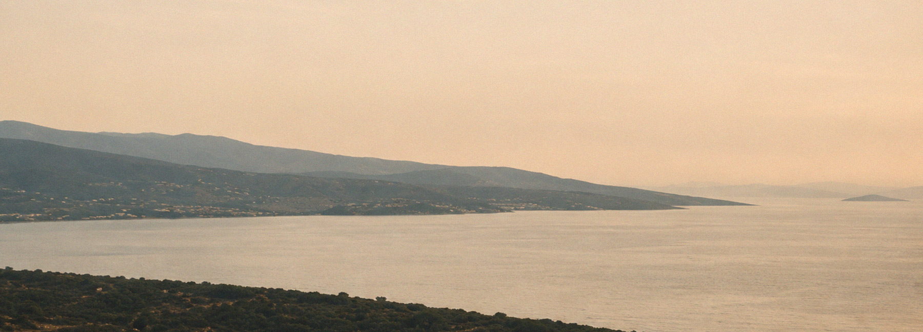 Expansive coastal landscape with sea and mountains in warm light – hero teaser for the ROSNER Studio Sale