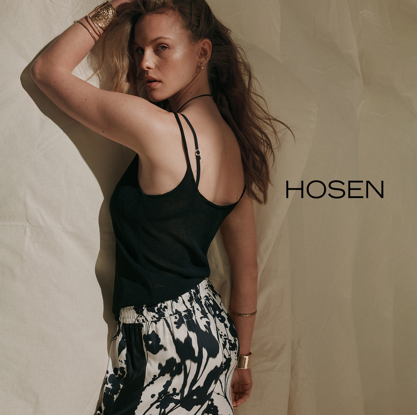 Modell im schwarzen Stricktop und weiter Hose mit floralem Print – Teaser zur Kategorie Hosen von ROSNER