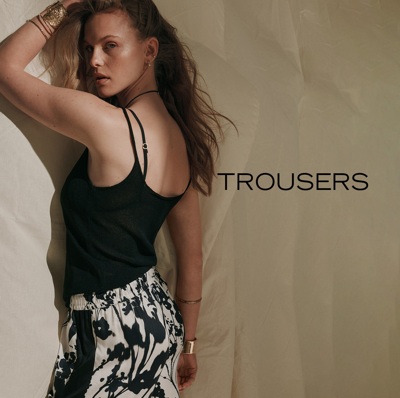 Model wearing a black knit top and wide-leg trousers with a floral print – teaser for the ROSNER trousers category