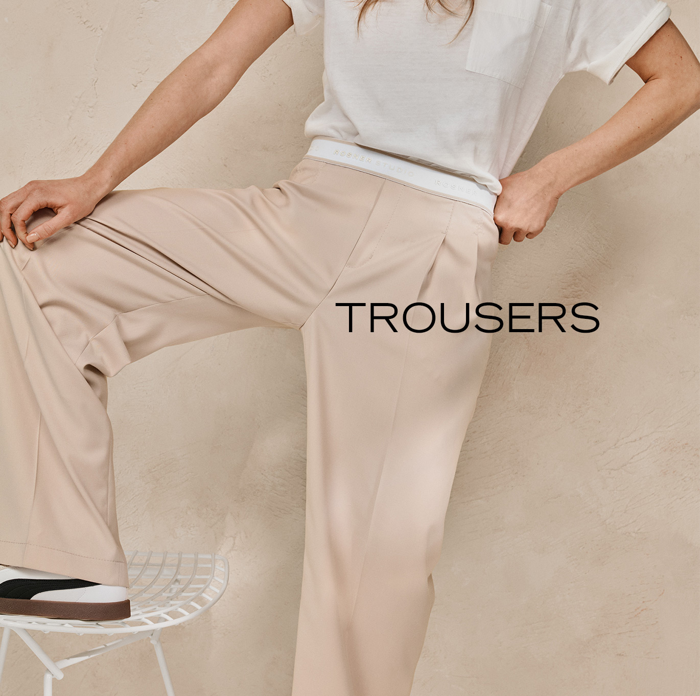 Woman wearing flowing beige wide-leg trousers and a simple shirt – teaser for Rosner Studio’s trousers category.