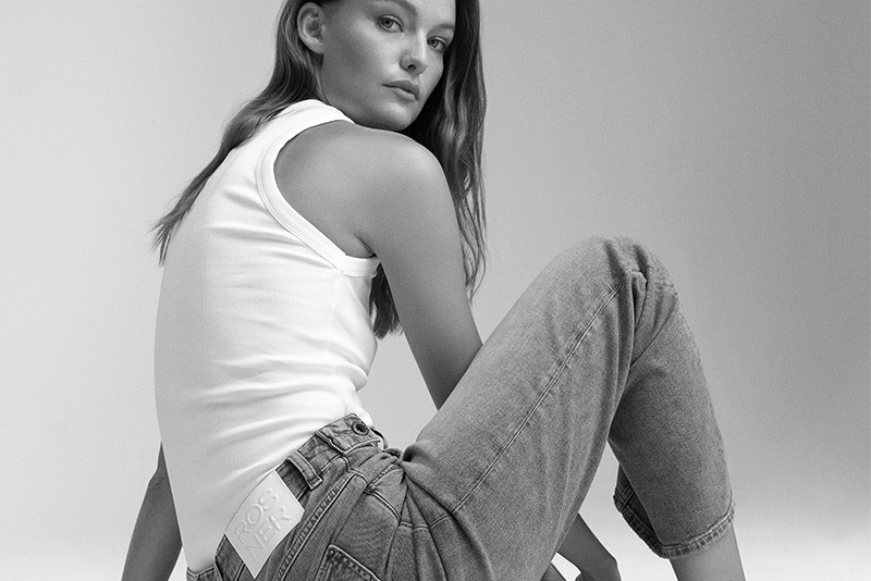 Kundenservice – wir sind für Sie da Frau in Jeans und Top sitzt seitlich – Visual für den Kundenservice bei ROSNER.