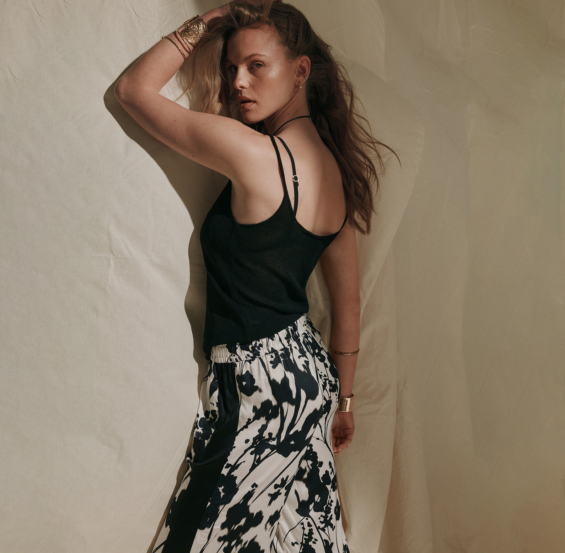 Model wearing a black top and wide-leg trousers with a floral print against a studio backdrop – teaser for all Rosner Studio looks
