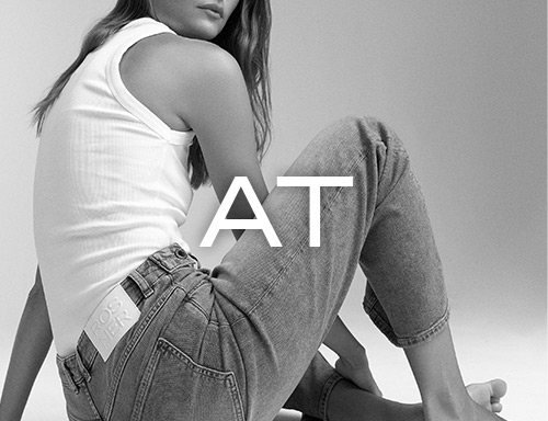 Frau in Jeans und weißem Top sitzt locker – Visual zur Retourenabwicklung aus Österreich bei ROSNER.