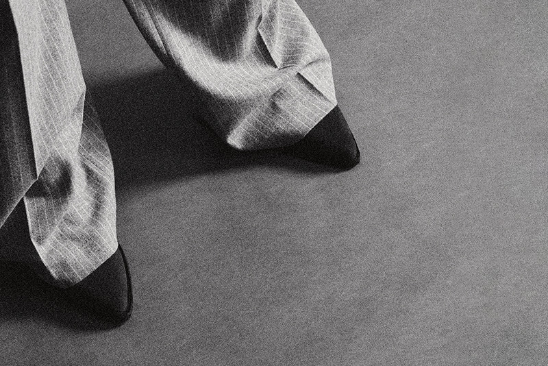Schwarz-Weiß-Aufnahme einer weit geschnittenen, gestreiften Rosner Hose mit spitzen schwarzen Schuhen.